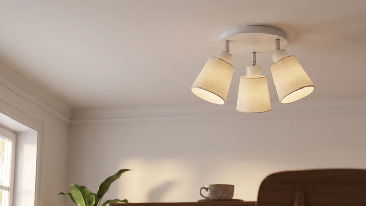 Weiße Rigipsdecke mit schwenkbarem Deckenstrahler mit Leinen-Schirm in einem hellen Wohnzimmer