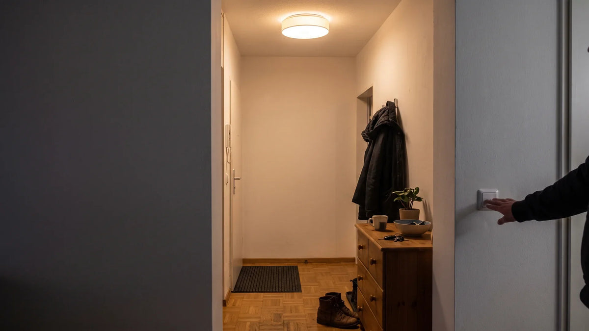 Nächtlicher Flur: Eine Hand am Wandschalter, doch die Deckenleuchte brennt weiterhin